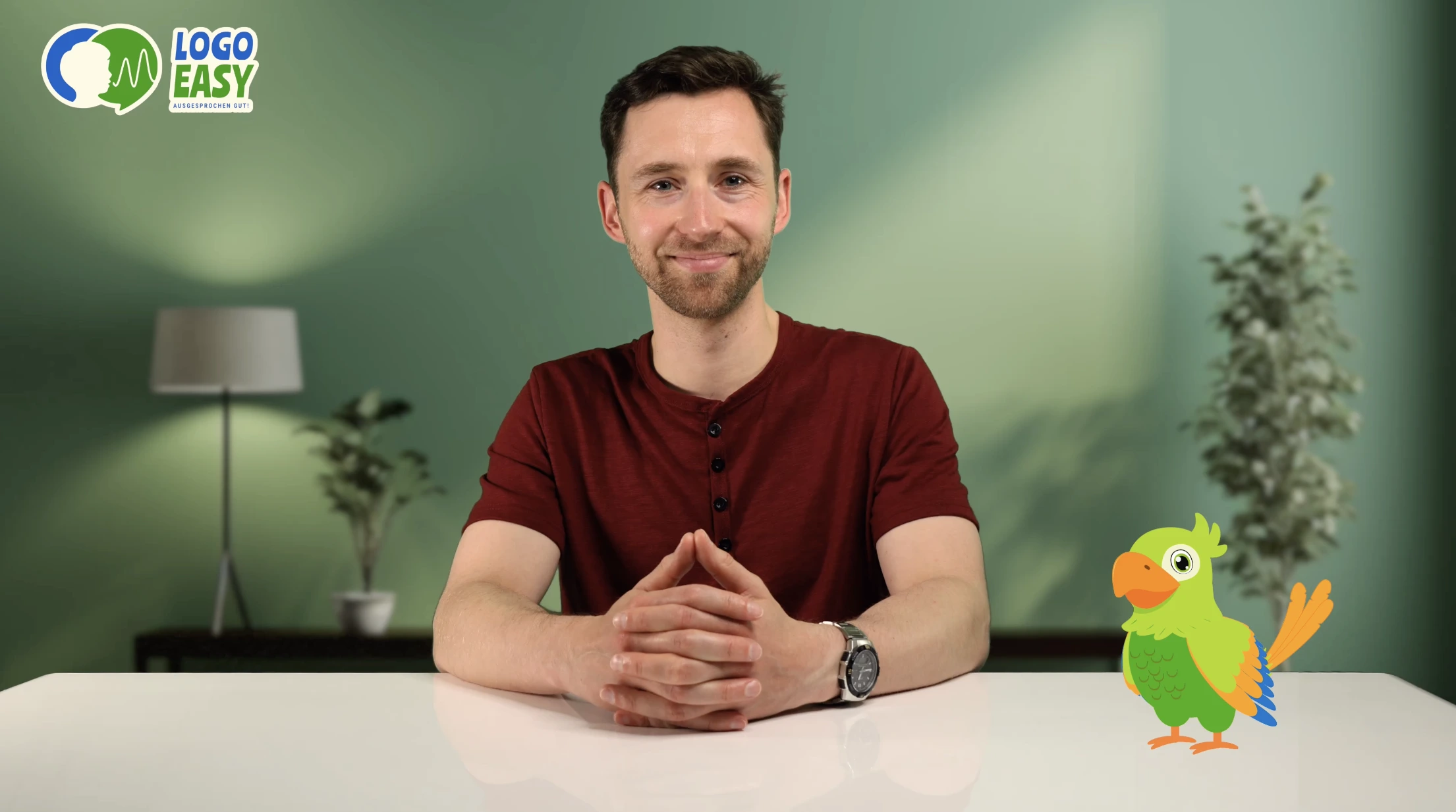 Logopäde sitzt mit dem Logo Easy Maskottchen Rikki und erklärt wissenschaftliche Grundlagen.